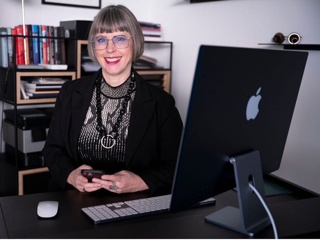 Karin Stehr an ihrem Schreibtisch mit iMac und Handy